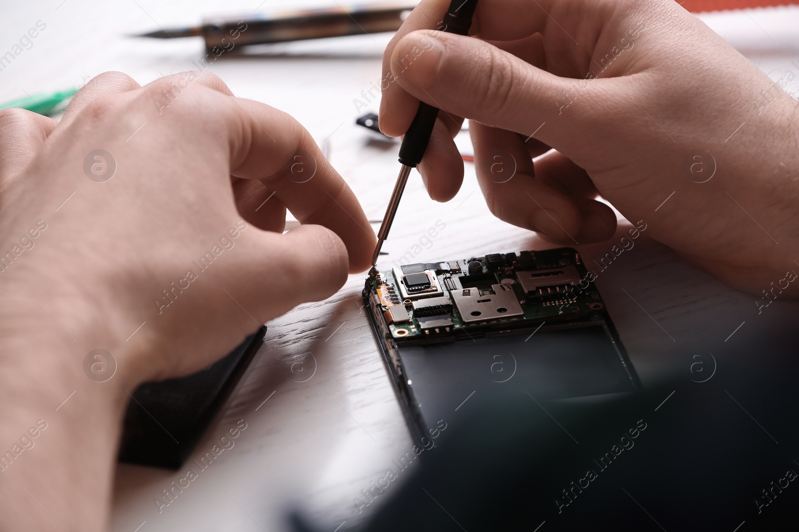 Photo of Technician fixing mobile phone at table, closeup. Device repair service