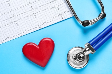 Photo of Cardiogram report, red wooden heart and stethoscope on light blue background, flat lay