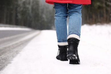 Photo of Woman walking outdoors on snowy winter day. Space for text
