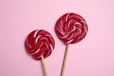 Photo of Sticks with bright lollipops on pink background, flat lay