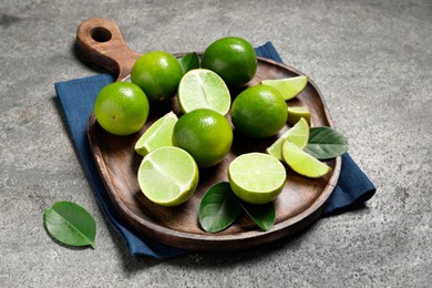 Photo of Fresh ripe limes and leaves on grey table