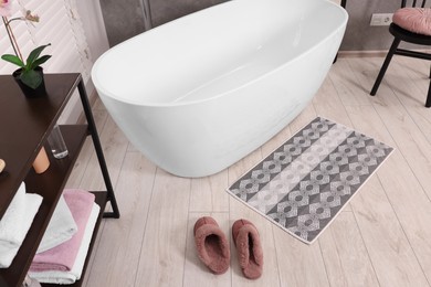 Photo of Stylish bathroom interior with soft bath mat and tub, above view