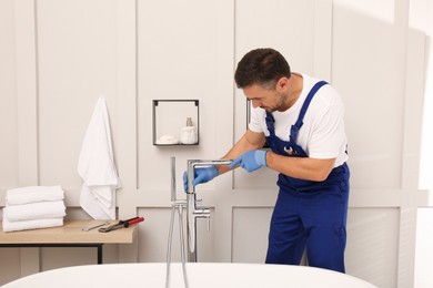 Professional plumber installing water tap in bathroom