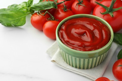 Bowl of tasty ketchup, tomatoes and basil on white marble table, closeup. Space for text