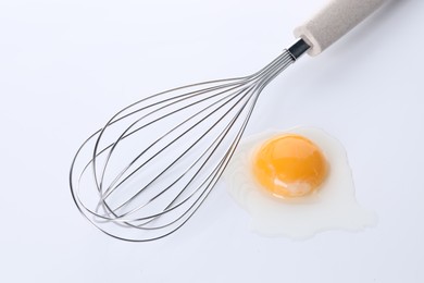Photo of Whisk and raw egg isolated on white