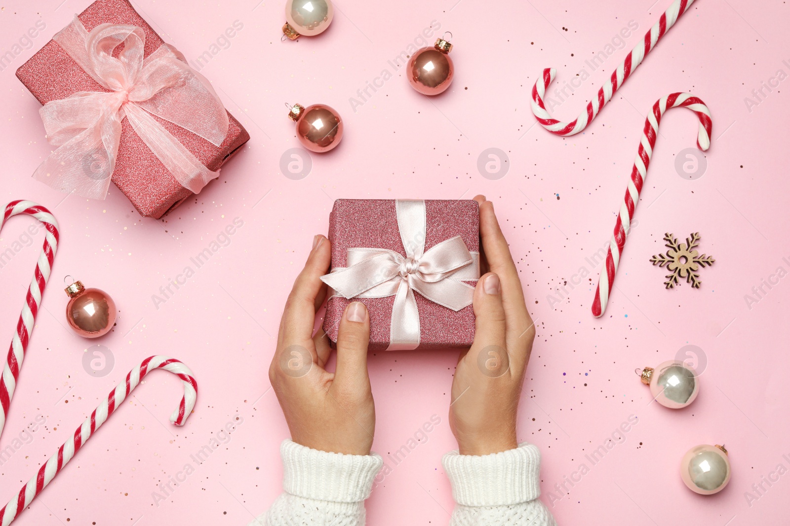 Photo of Young woman holding Christmas gift on pink background, flat lay