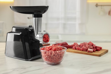 Photo of Electric meat grinder with minced beef on white marble table in kitchen