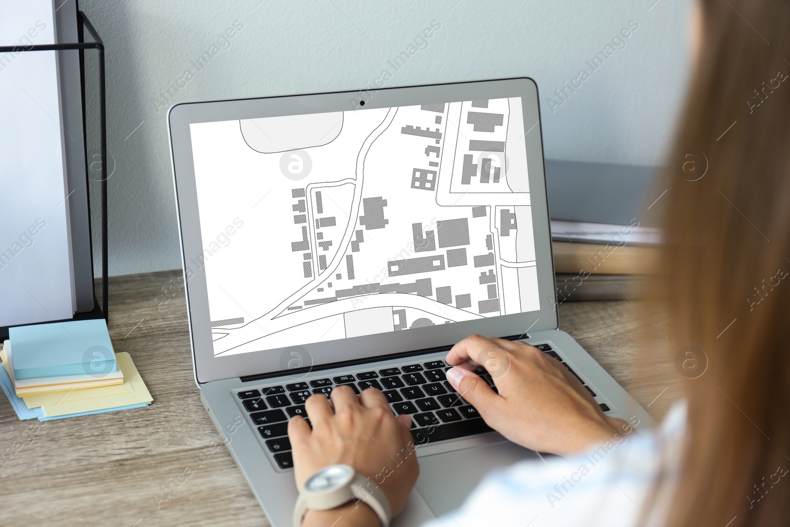 Image of Woman analyzing cadastral map on laptop at table, closeup 