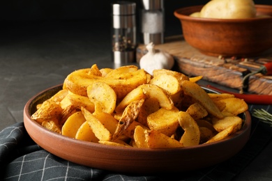 Photo of Plate of delicious oven baked potatoes on table, closeup