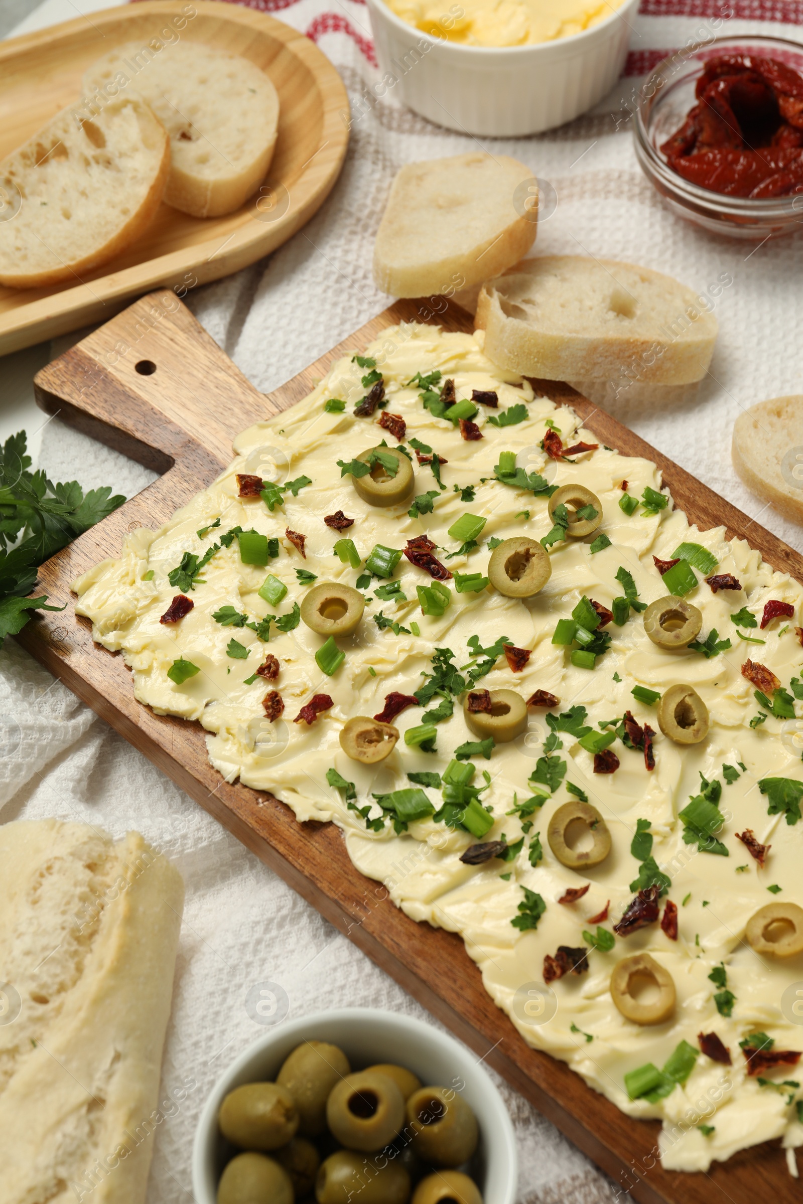 Photo of Fresh butter board with cut olives, sun-dried tomatoes and bread on table, above view