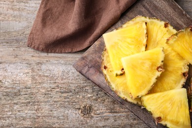 Pieces of tasty ripe pineapple on wooden table, top view. Space for text