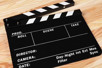 Photo of One black movie clapperboard on wooden table
