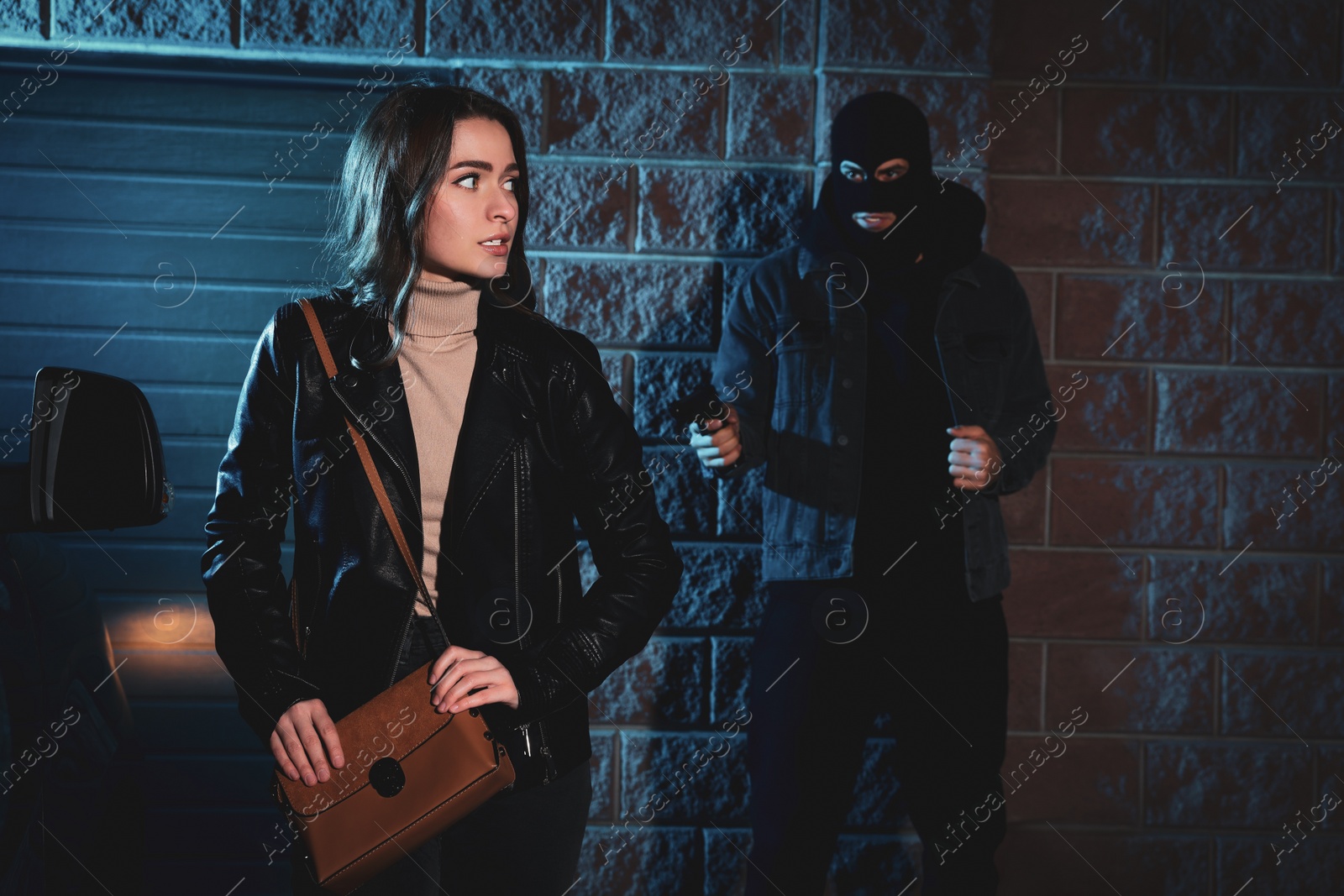 Photo of Criminal threatening young woman with gun outdoors at night. Self defense concept