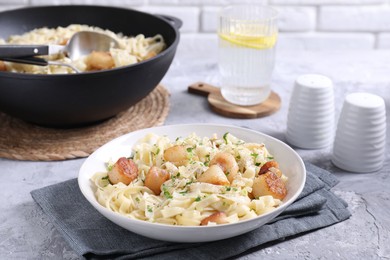 Delicious scallop pasta with spices in bowl on gray textured table