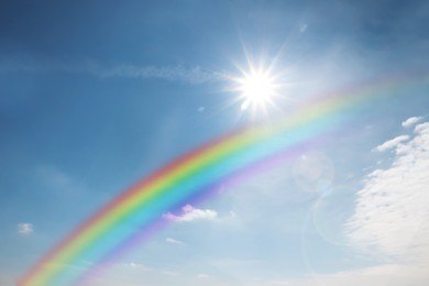 Image of Beautiful rainbow in blue sky with white clouds on sunny day