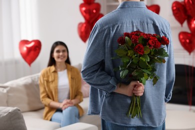 Photo of Man hiding bouquet of red roses for his beloved woman, closeup. Valentine's day celebration