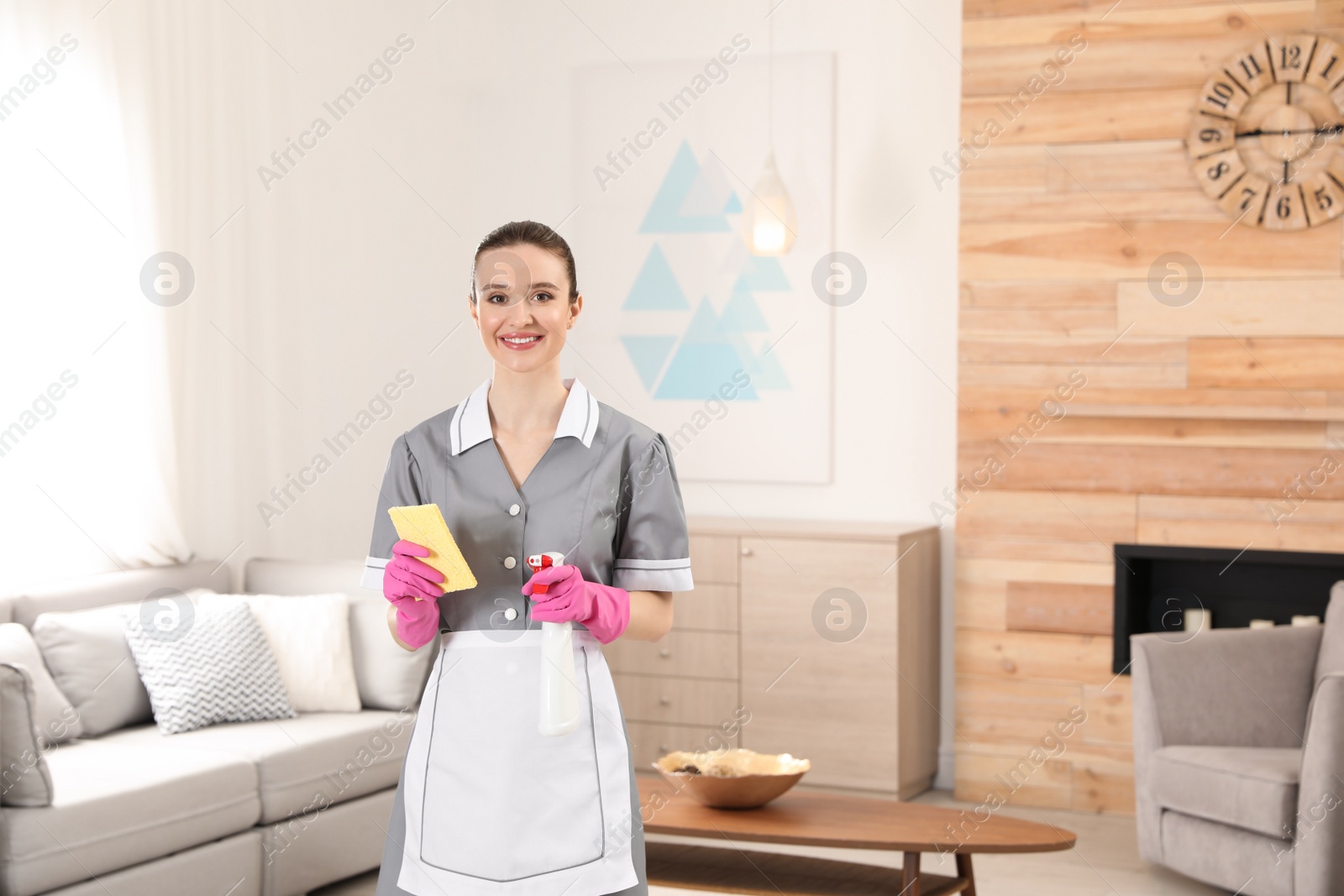 Photo of Portrait of young chambermaid with cleaning supplies in hotel room. Space for text