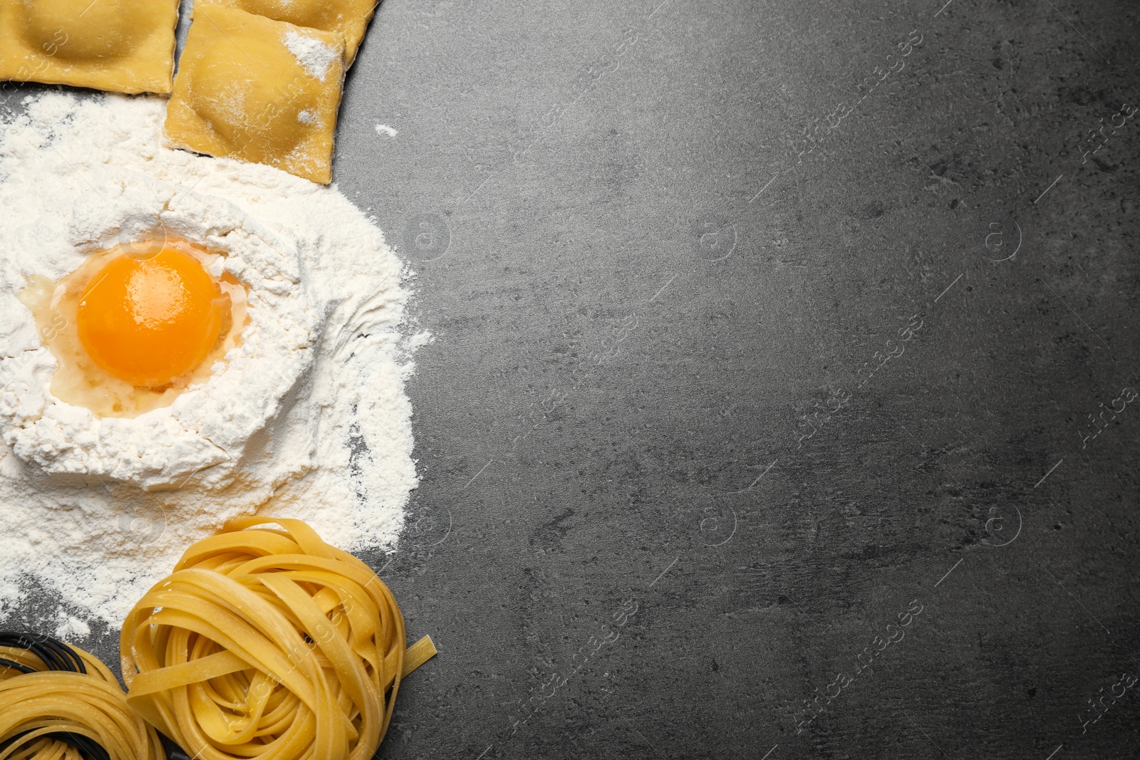 Photo of Flat lay composition with different types of pasta on grey table. Space for text