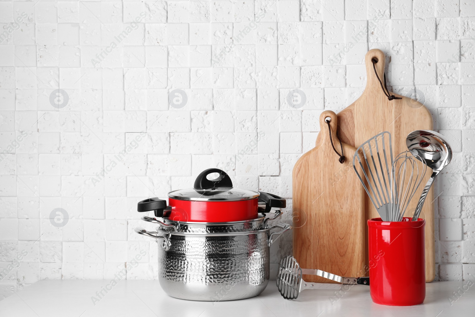 Photo of Set of clean  cookware and utensils on table against white wall, space for text