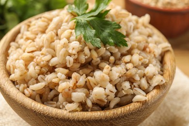 Photo of Delicious pearl barley with parsley in bowl on table, closeup