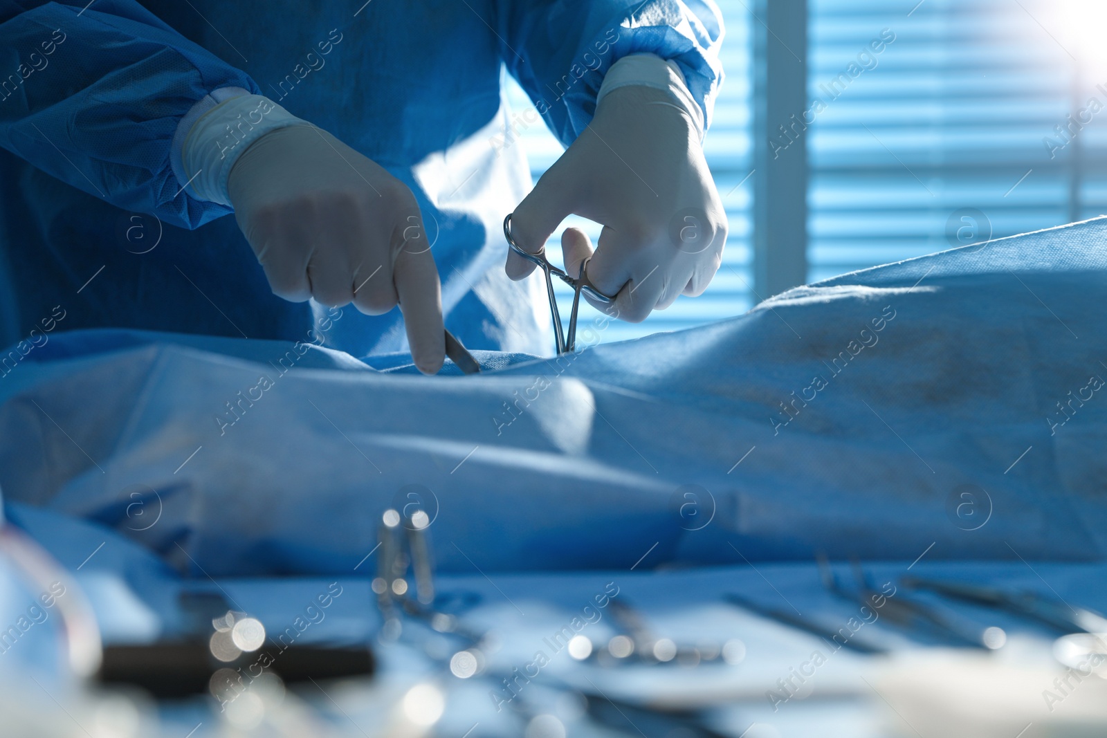 Photo of Professional surgeon with instruments performing operation in clinic, closeup