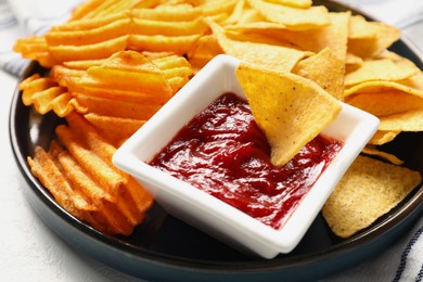 Tasty tortilla and ridged chips with ketchup on white table, closeup