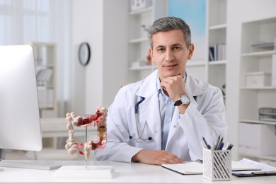 Photo of Gastroenterologist with anatomical model of large intestine at table in clinic