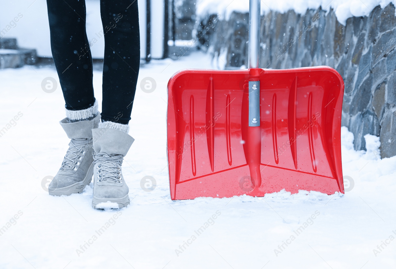 Photo of Woman with red snow shovel outdoors. Winter weather