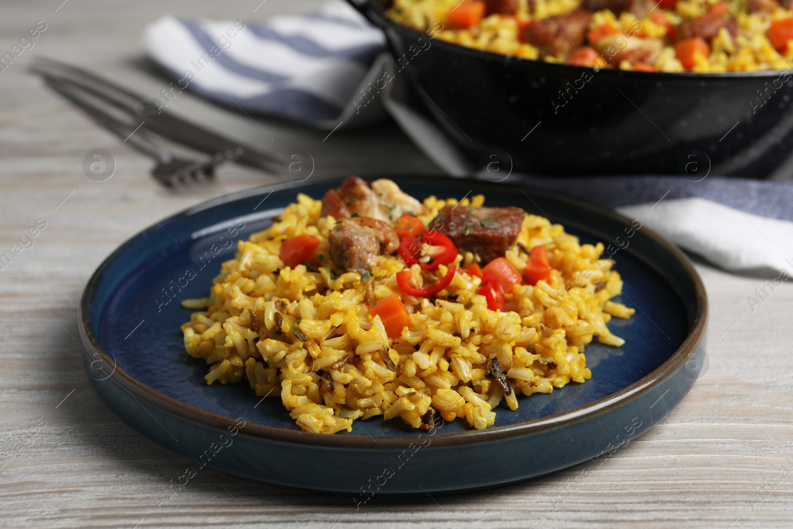 Photo of Delicious pilaf with meat, carrot and chili pepper on wooden table, closeup