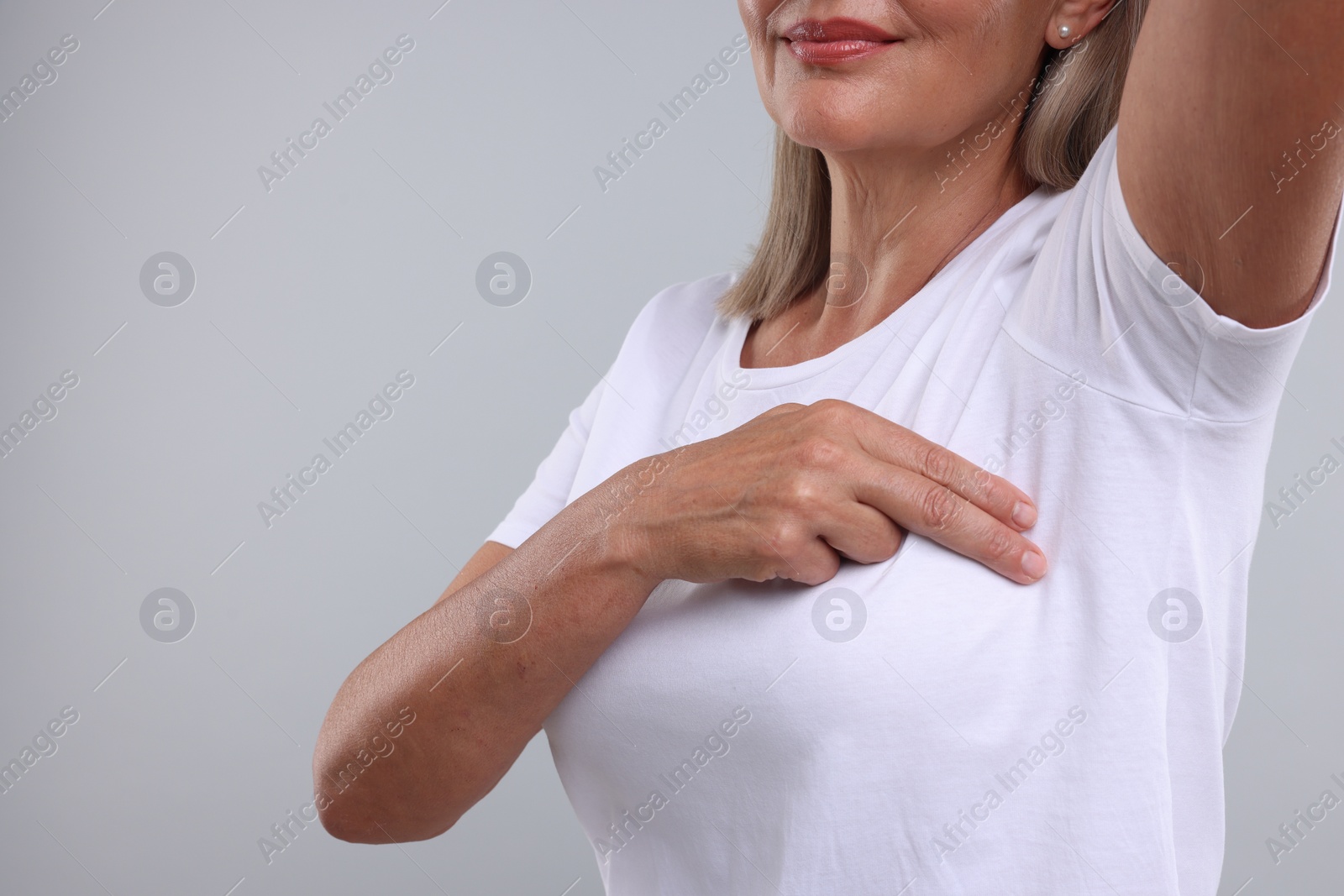 Photo of Woman doing breast self-examination on light grey background, closeup. Space for text