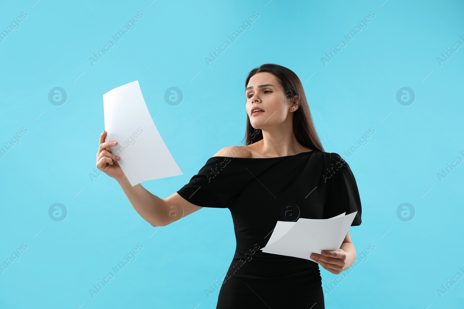 Photo of Emotional actress with script performing on light blue background. Film industry