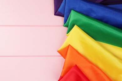 Rainbow LGBT flag on pink wooden table, top view. Space for text