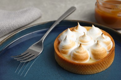 Photo of Tartlet with meringue on grey table, closeup. Delicious dessert