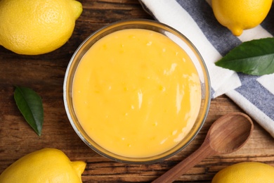 Delicious lemon curd and fresh fruits on wooden table, flat lay