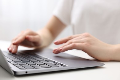 E-learning. Woman using laptop at white table indoors, closeup