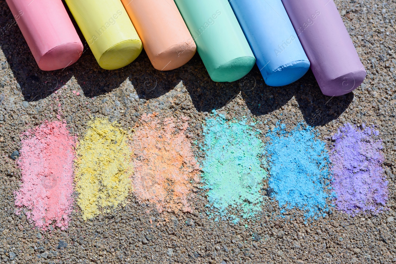 Photo of Colorful chalk sticks and strokes on asphalt outdoors, above view