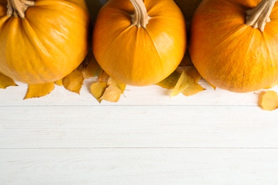 Ripe pumpkins on wooden background, flat lay with space for text. Holiday decoration