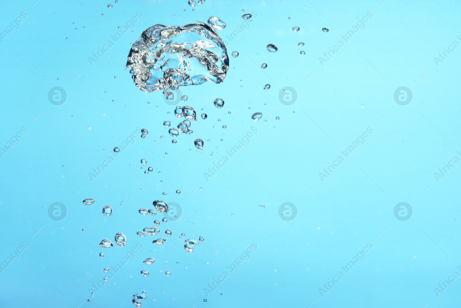 Photo of Air bubbles in water on light blue background