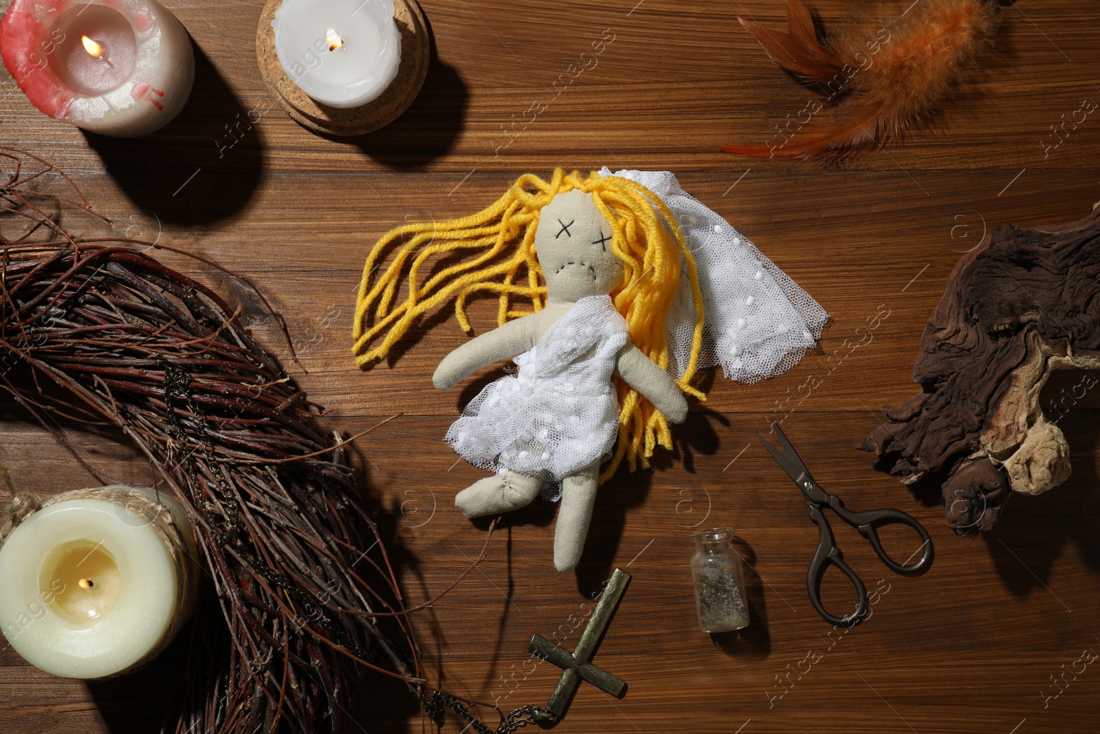Photo of Bride voodoo doll with pins surrounded by ceremonial items on wooden background, flat lay