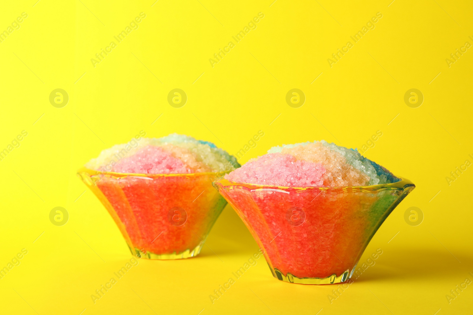 Photo of Rainbow shaving ice in glass dessert bowls on yellow background