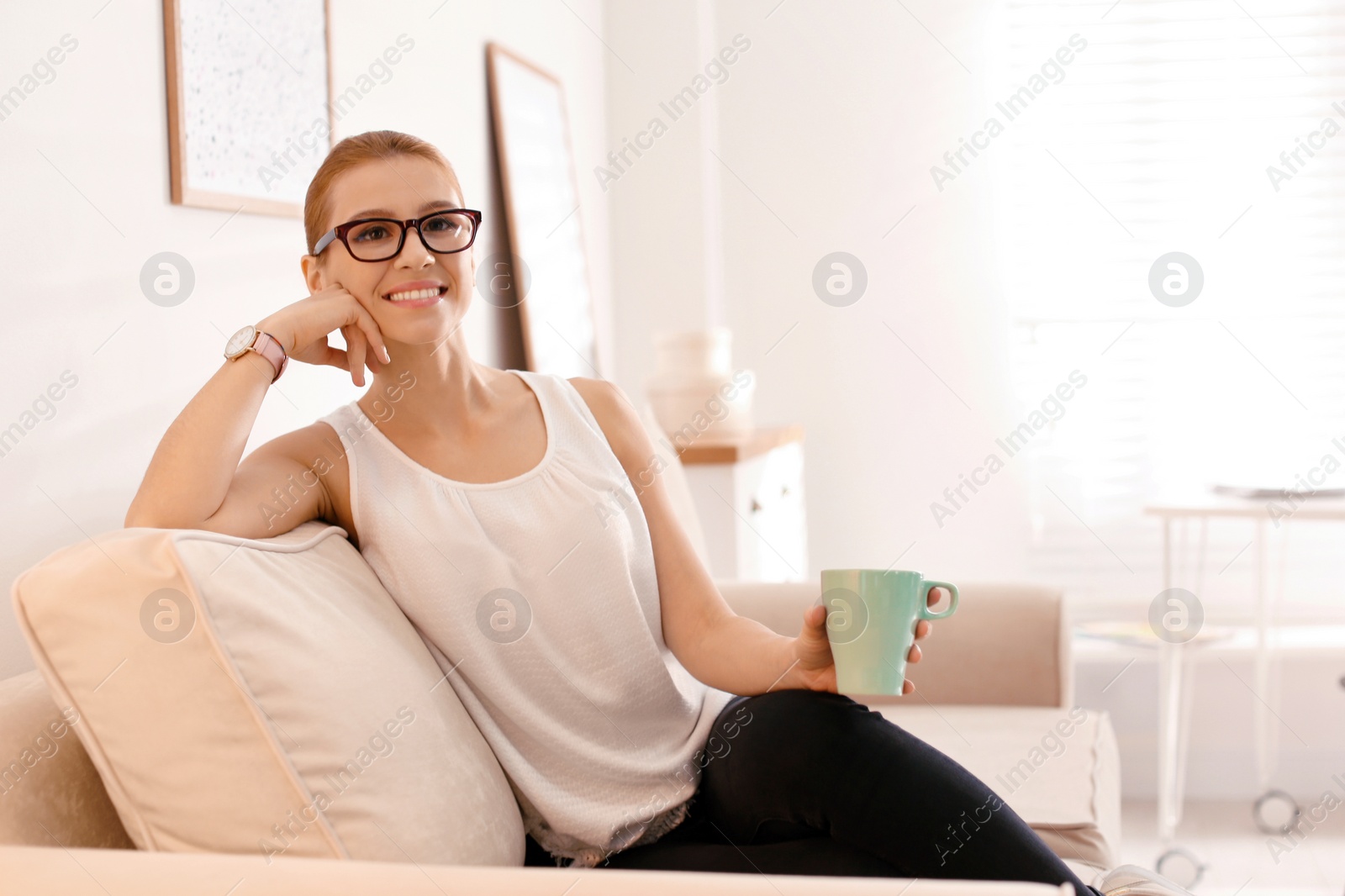 Photo of Young woman with cup of drink relaxing on couch in office