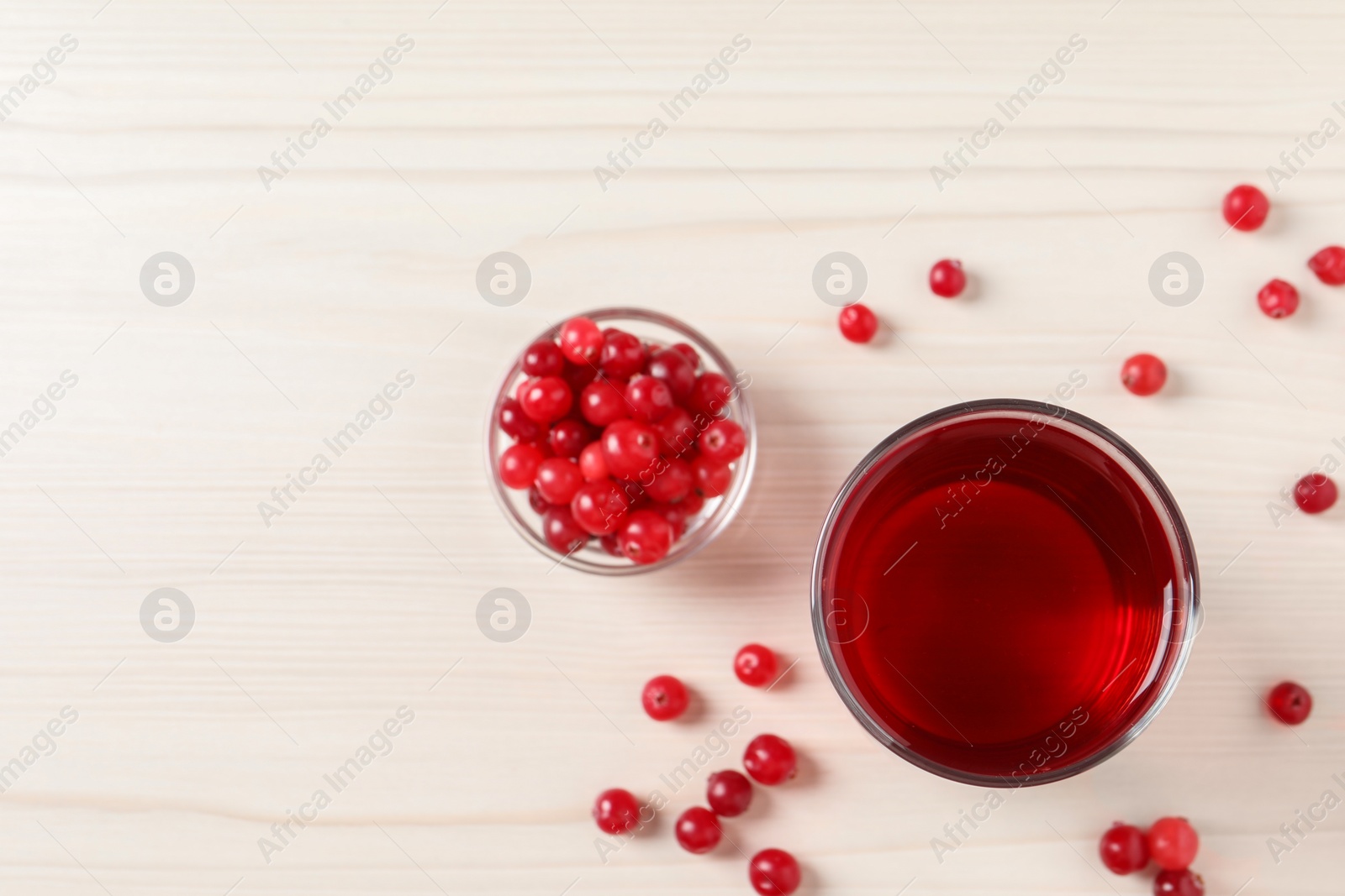 Photo of Tasty cranberry juice in glass and fresh berries on white wooden table, flat lay. Space for text