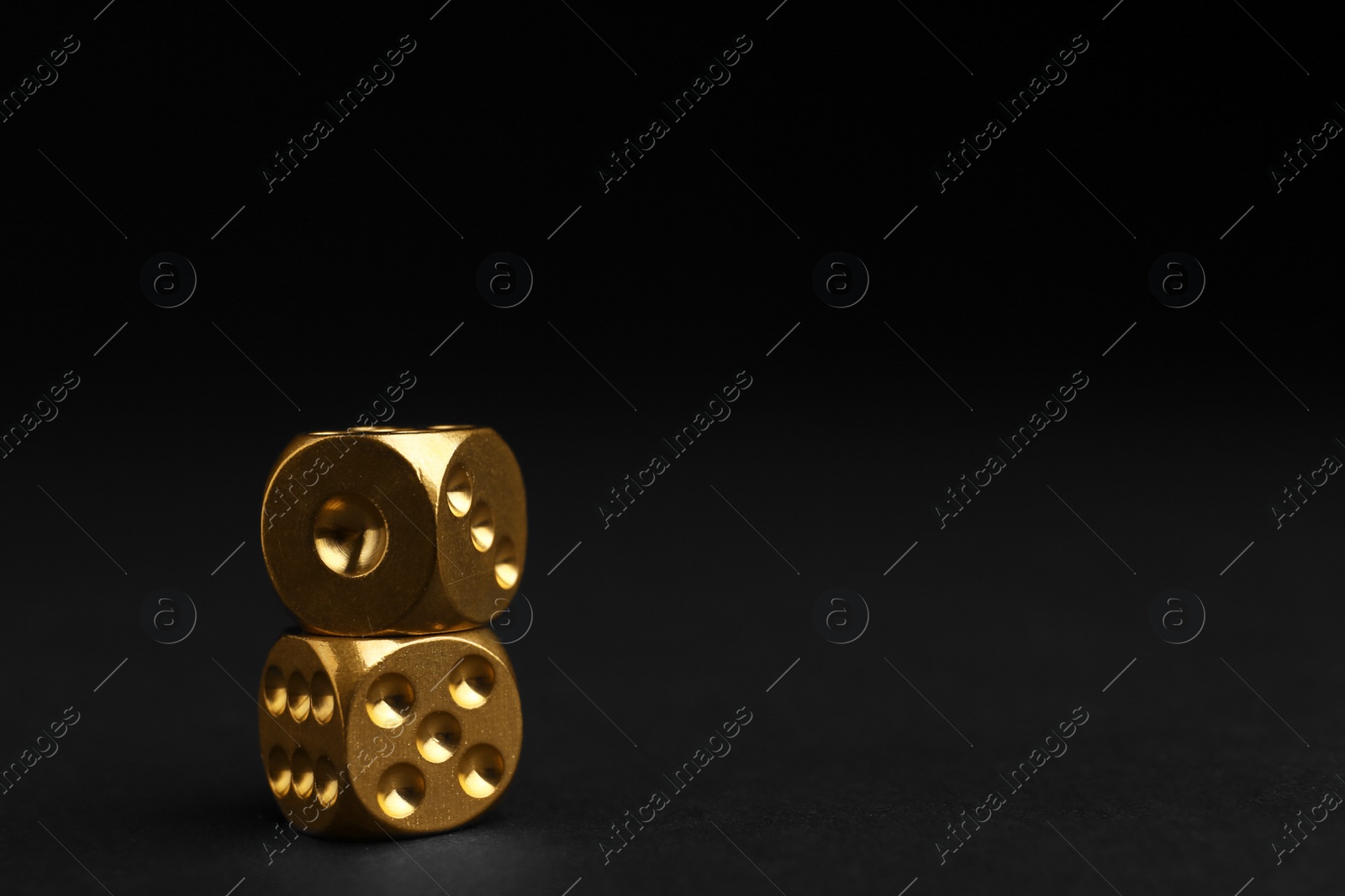 Photo of Stacked gold dices on black background. Space for text