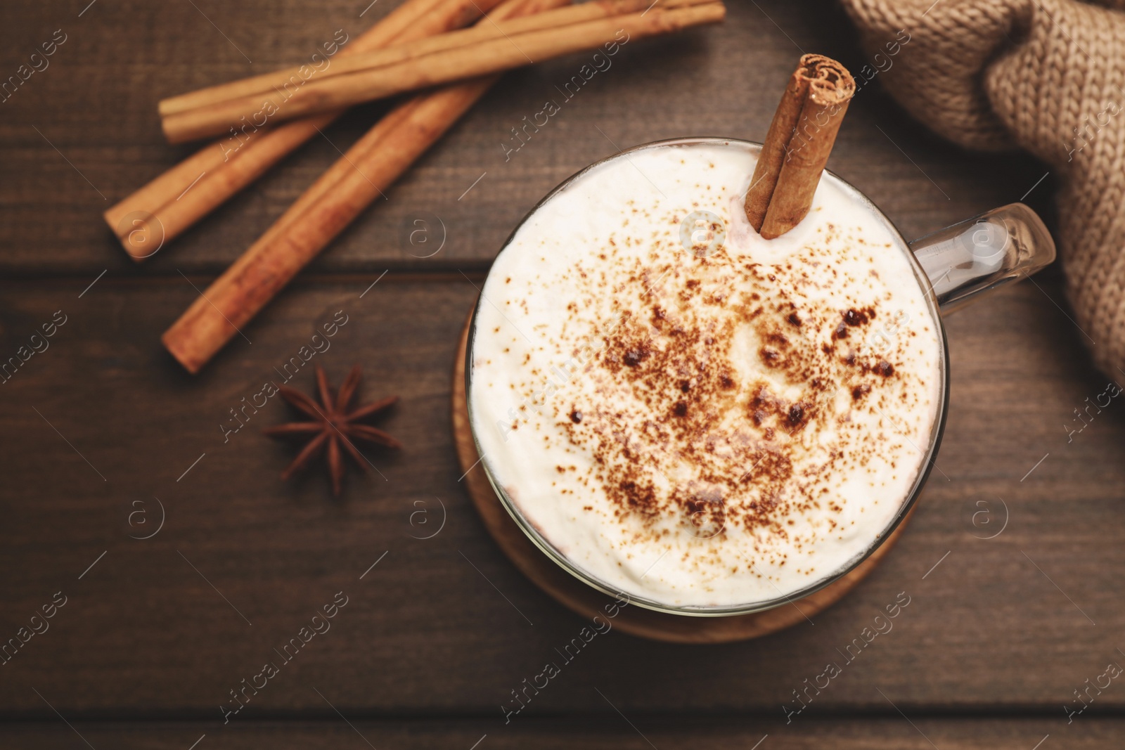 Photo of Cup of hot drink with whipped cream and aromatic cinnamon on wooden table, flat lay