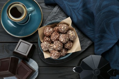 Delicious sweet chocolate candies, bars and coffee on black wooden table, flat lay
