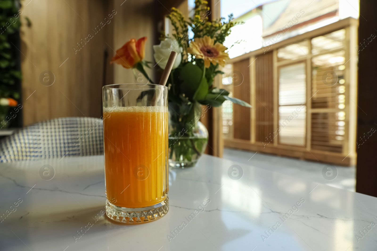 Photo of Glass of fresh orange juice on white table in cafeteria