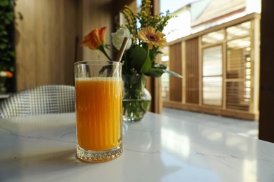 Photo of Glass of fresh orange juice on white table in cafeteria