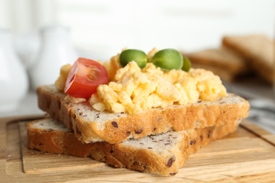 Photo of Tasty scrambled egg sandwich on wooden board, closeup