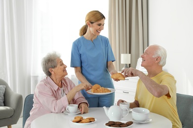 Photo of Nurse assisting while elderly people having breakfast at retirement home