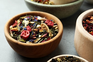 Photo of Bowls with different herbal teas on grey table